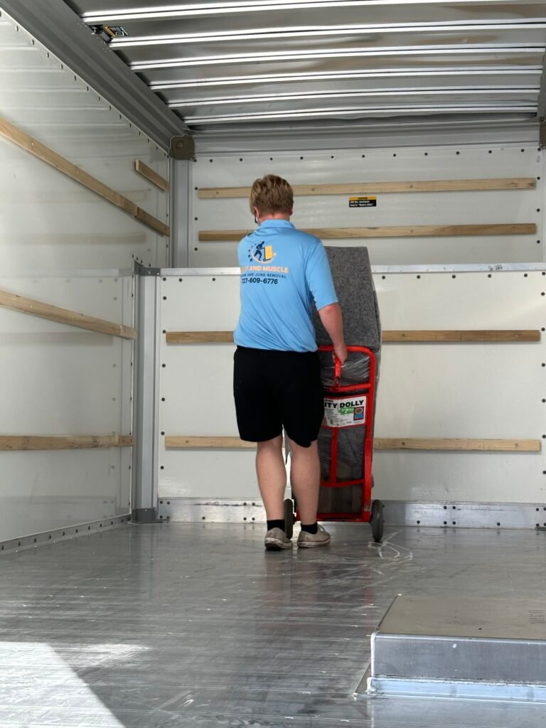 Tampa Bay movers loading furniture onto moving truck Merit and Muscle