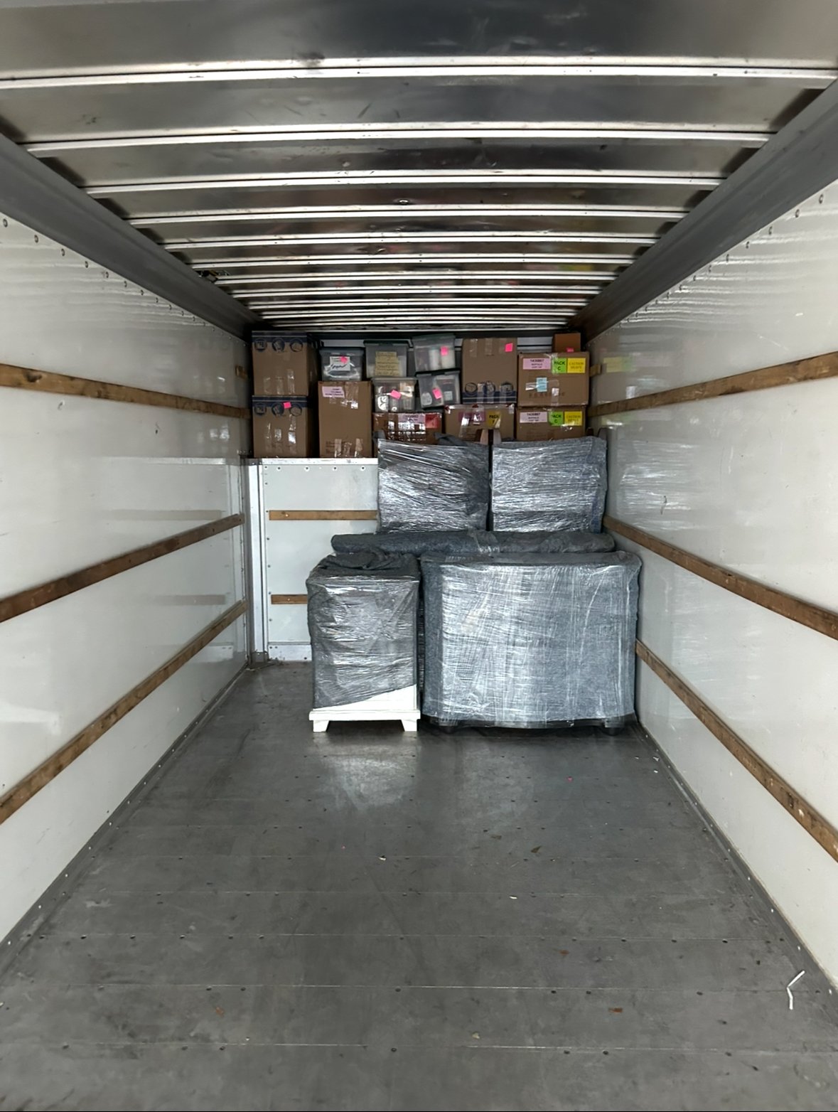 Emergency Movers Wesley Chapel 1 Real photo looking inside a clean, spacious moving truck cargo bed, neatly packed with organized and wrapped furniture and moving boxes.