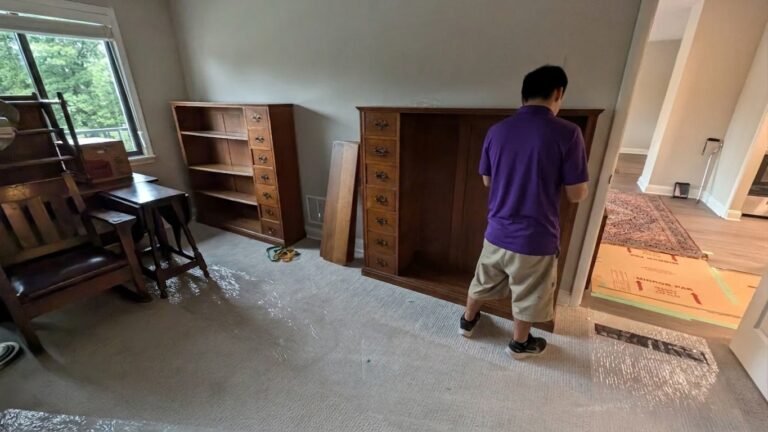 Mover handling an antique wood bookcase on protected carpet in South Tampa, FL