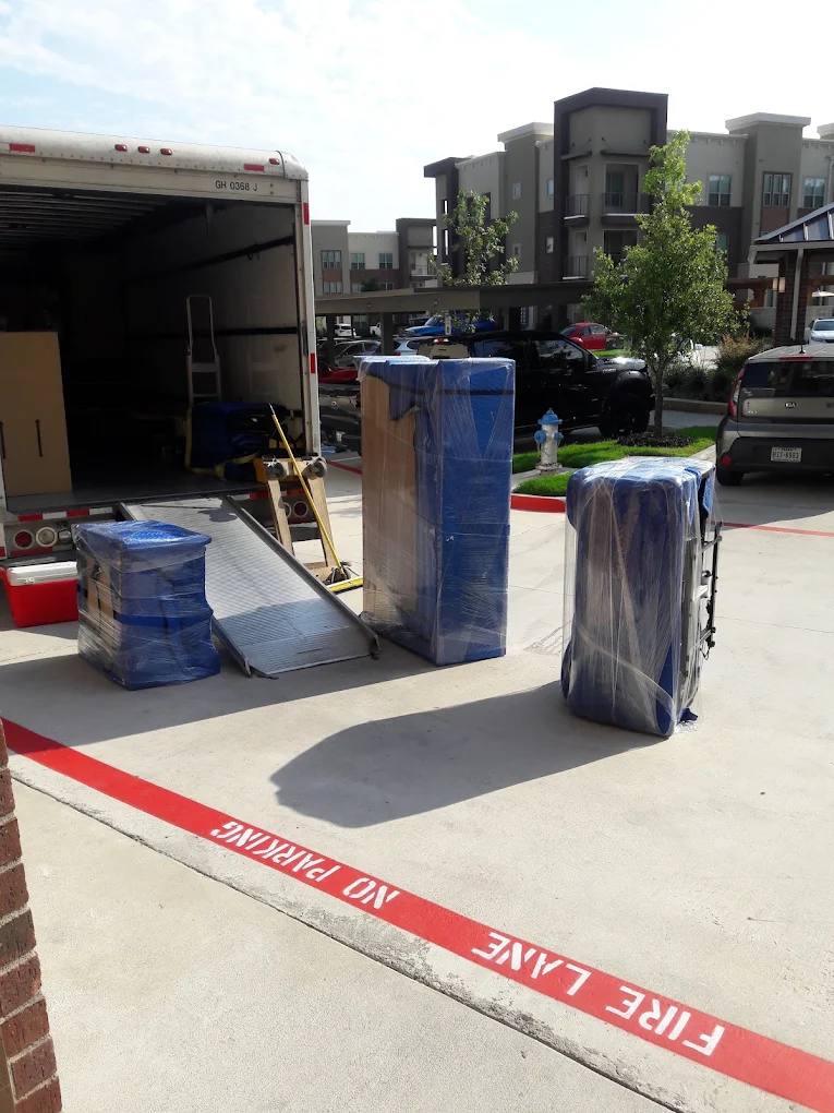 Apartment & Townhome Movers in Wesley Chapel, FL 1 Padded and wrapped furniture staged beside a moving truck ramp at an apartment complex