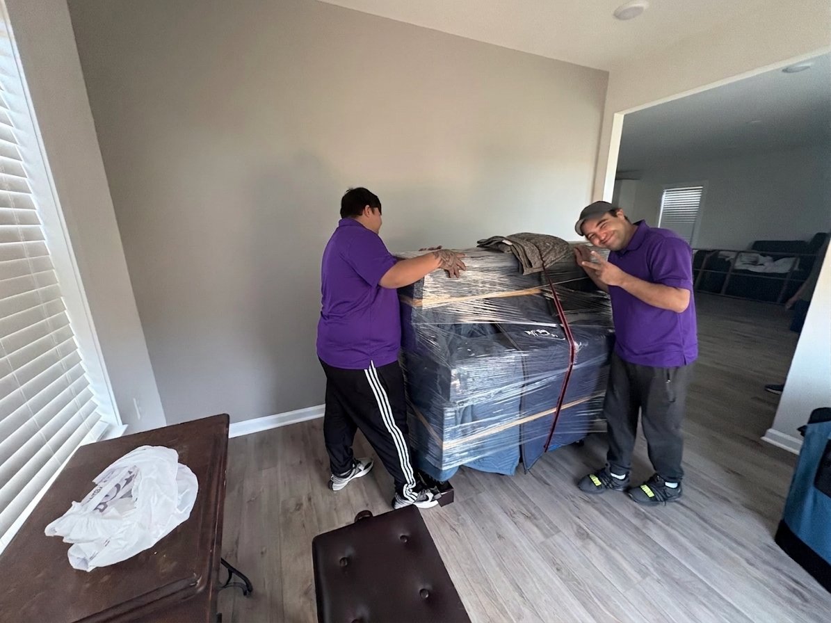 Wesley Chapel Movers 3 Two movers with a padded and shrink-wrapped piece of furniture in Wesley Chapel, FL