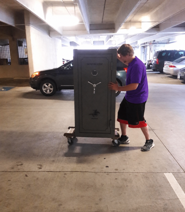 Mover rolling a gun safe on a dolly through a parking garage in Carrollwood, FL
