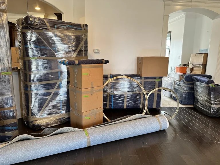 Living room furniture padded, wrapped and labeled with boxes and a rolled rug in Riverview, FL