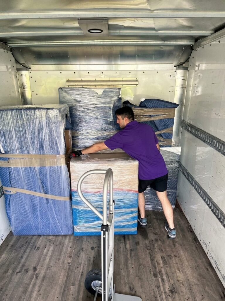 Mover stacking padded and wrapped furniture inside a box truck in Wesley Chapel, FL