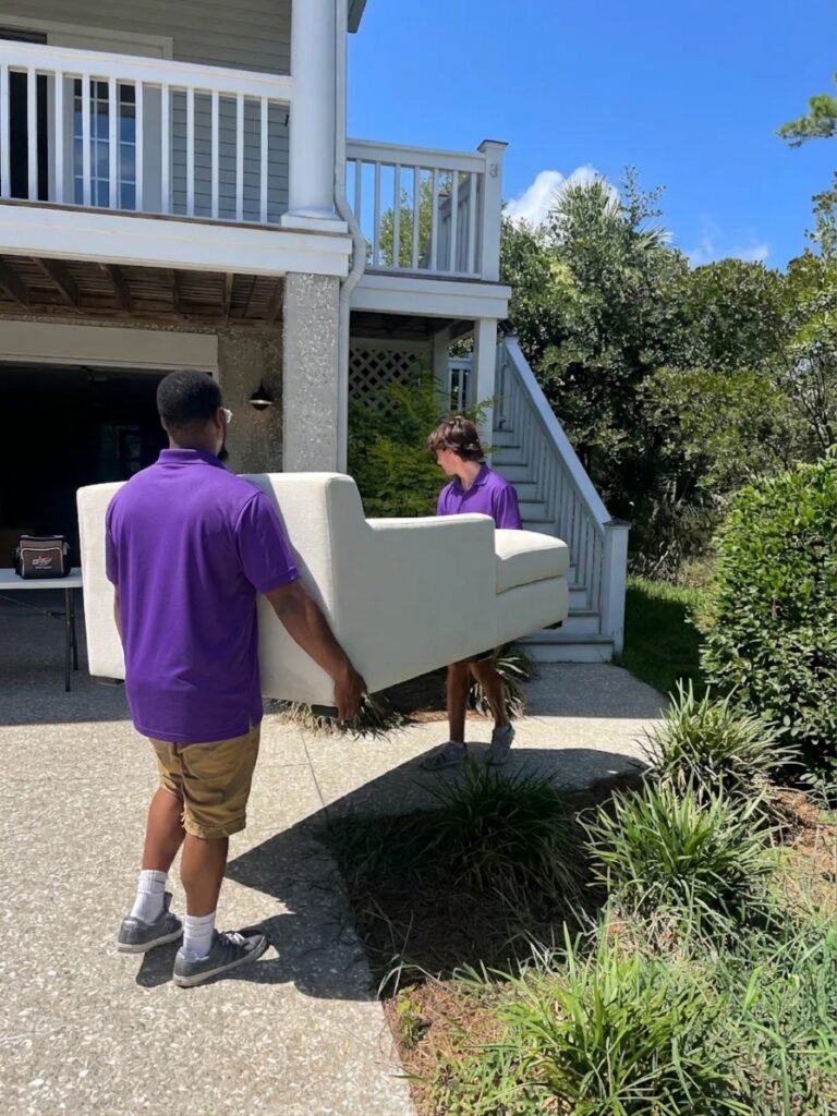 Two movers carrying a white sofa out of a home in Odessa, FL