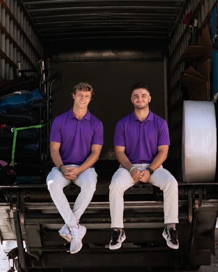 Best Places to Live in Tampa (2026 Guide) 1 Two movers in purple polos sitting on the back of a moving truck in Tampa, FL