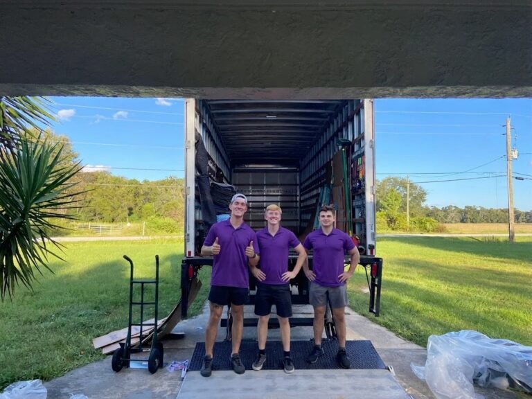 Movers in Dover, FL 1 Three movers in purple polos standing at the back of a moving truck