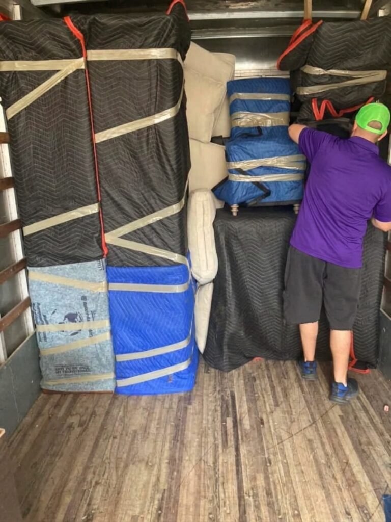 Mover loading blanket-wrapped furniture tightly into a moving truck in Brandon, FL