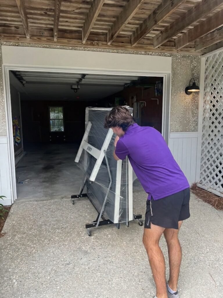 Mover rolling a shrink-wrapped ping pong table into a garage in Westchase, FL