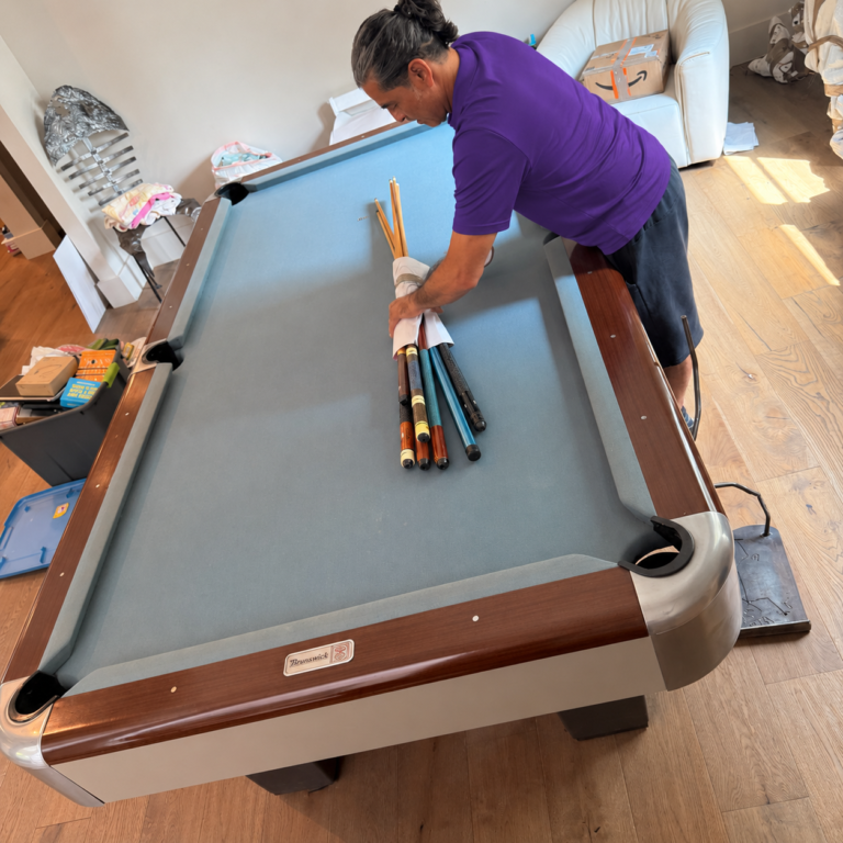 Gun Safe & Heavy Item Movers in Plant City, FL 1 Mover bundling pool cues on a pool table before disassembly