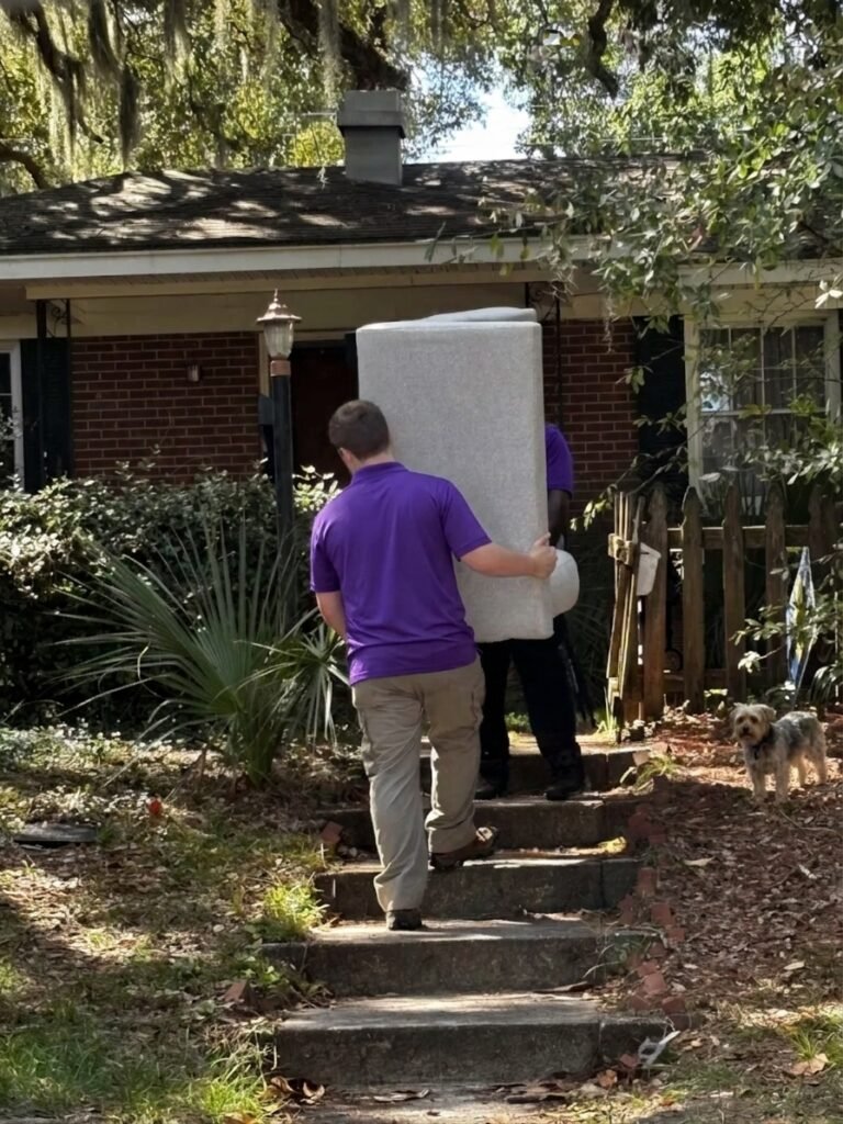 Two movers carrying an upholstered chair up the front steps of a home in Seminole Heights, Tampa, FL