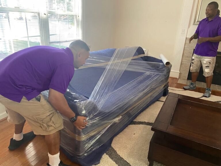 Movers shrink-wrapping a blanket-padded sofa in Brandon, FL