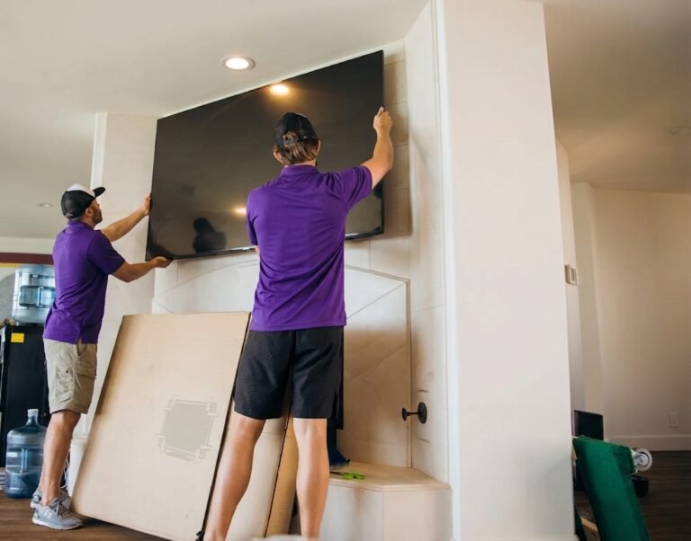 Two movers mounting a large TV above a fireplace in New Tampa, FL
