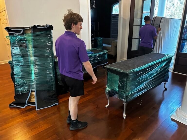 Movers carrying out padded and stretch-wrapped furniture from a home in South Tampa, FL